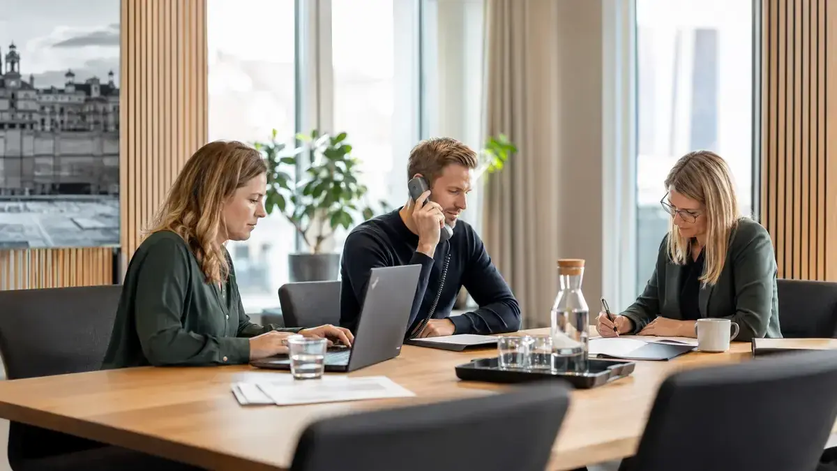 Mitarbeiter im modernen Büro mit Laptop und Telefon mit Unternehmenssymbol – Symbolbild zum Beitrag „Ausstehende Forderungen gegenüber Verbrauchern: Kommunikation und Verzug sauber gestalten“.