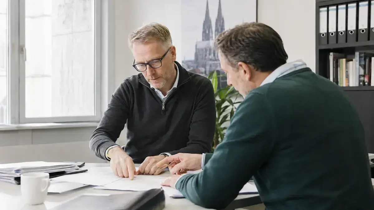 zwei Fachleute bei der gemeinsamen Prüfung eines Geschäftsvorgangs mit Unternehmenssymbol.