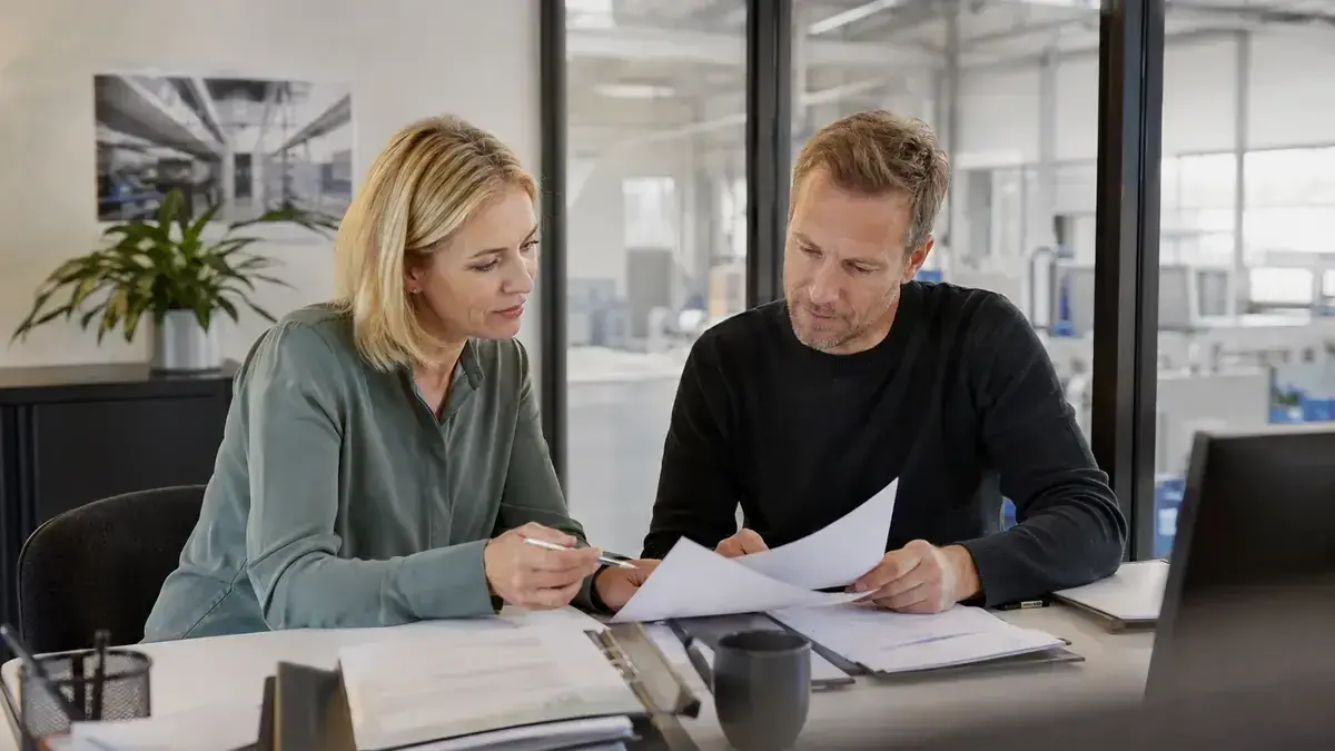 zwei Fachleute bei der gemeinsamen Prüfung eines Geschäftsvorgangs mit sachlichem Partnerschaftssymbol – Symbolbild zum Beitrag „Forderungsmanagement auslagern: Chancen, Kosten und Kontrollpunkte“.