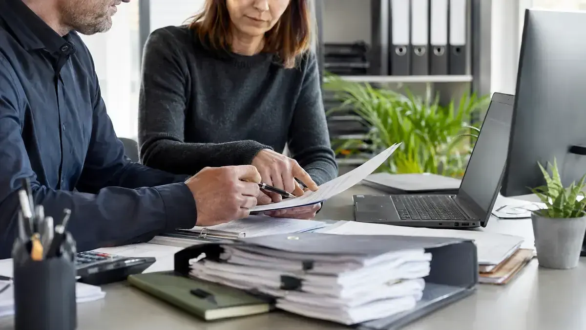 Two professionals jointly reviewing a business case with organised digital receivables folder – editorial image for “Receivables management starts with the invoice: how to avoid errors before due date”.