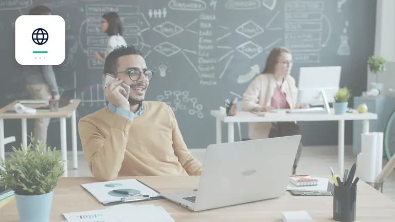 Mitarbeiter im modernen Büro mit Laptop und Telefon mit Globus für grenzüberschreitende Fälle – Symbolbild zum Beitrag „Forderungsmanagement und EU-Zahlungsverzug: Stand der geplanten Neuregelung“.