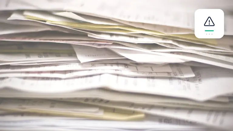 Facturas y documentos empresariales ordenados con símbolo de alerta y documentos empresariales – imagen editorial para «Cobro de deudas ante insolvencias empresariales crecientes: lecciones de las cifras de abril de…