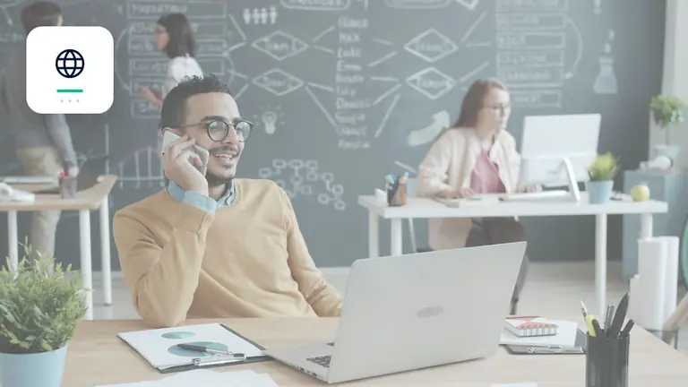 Professional in a modern office with a laptop and phone with globe for cross-border cases – editorial image for “Business debt collection abroad: how to check countries, language and enforceability”.