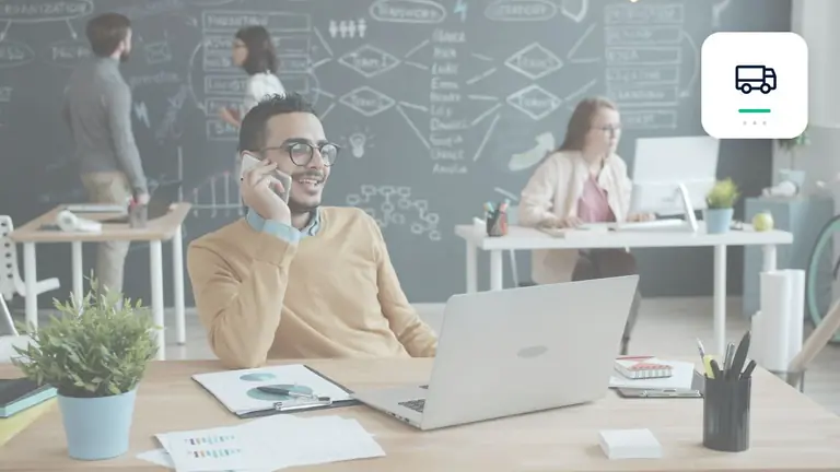 Professional in a modern office with a laptop and phone with transport and delivery symbol – editorial image for “Business debt collection in transport and logistics: freight documents as evidence”.
