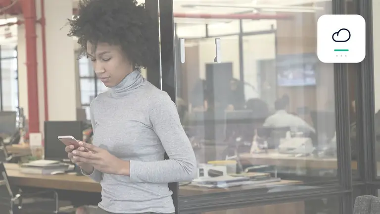 Professional using a smartphone in a transparent modern office with cloud and billing symbol – editorial image for “Business debt collection with SaaS and subscription models: how to process recurring receivables at…