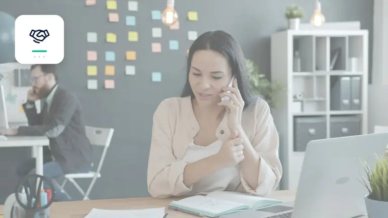 Professional speaking with a customer by phone at a laptop with professional partnership symbol – editorial image for “Business debt collection: when outsourcing pays off”.
