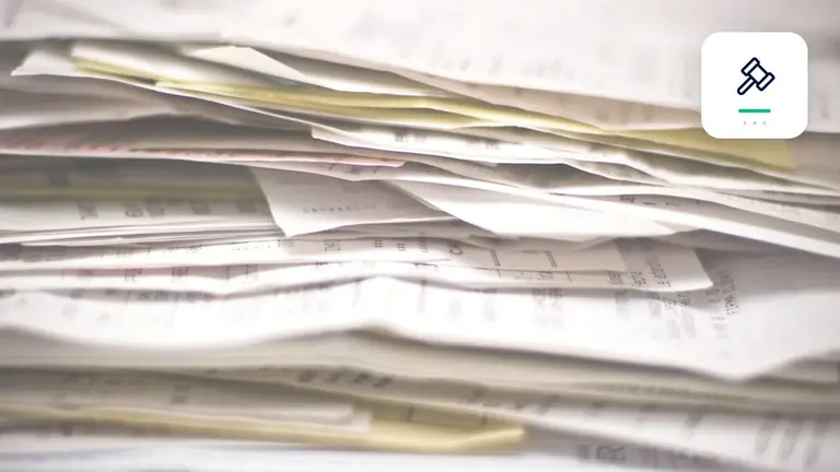 Facturas y documentos empresariales ordenados con símbolo judicial estilizado – imagen editorial para «Cobro de deudas o Mahnbescheid (requerimiento de pago judicial alemán): qué vía encaja con cada crédito?».