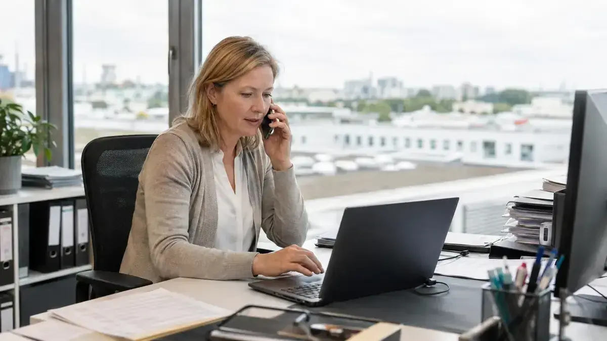 Professional speaking with a customer by phone at a laptop with personal business communication – editorial image for “Open receivables converted into dunning stages: how to plan deadlines and tone”.