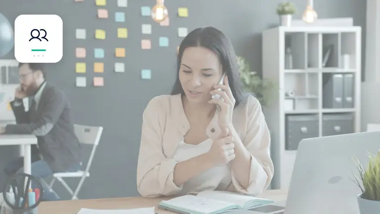 Profesional atendiendo por teléfono a un cliente junto a un portátil con comunicación empresarial personal – imagen editorial para «Partidas abiertas comunicación orientada al cliente: plantillas para recordatorio y…