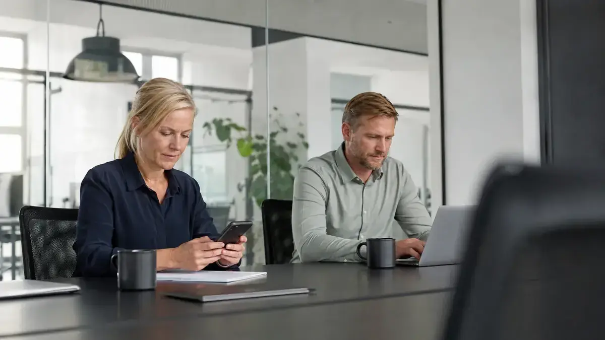 Mitarbeiterin mit Smartphone in einem transparenten modernen Büro mit Onlinehandel- und Zahlungssymbol – Symbolbild zum Beitrag „Rechnung wird nicht bezahlt im Online-Shop: Bestellung und Lieferung beweisen“.