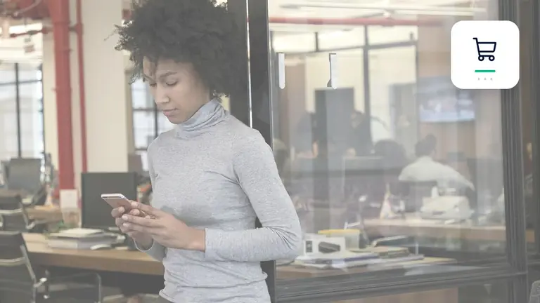 Profesional con un teléfono móvil en una oficina moderna y diáfana con símbolo de comercio electrónico y pago – imagen editorial para «Factura no pagada en tiendas online: cómo probar pedido y entrega».
